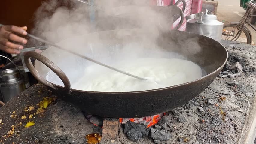 Live picture of heating milk in a pan in a shop inside Jharkhand city in market. No face.