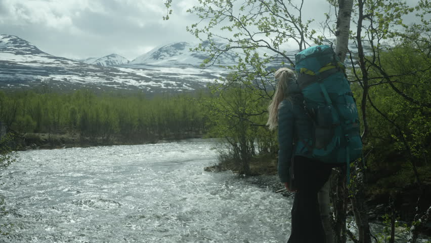 Blond Female Hiker Standing by the River on the Kungsleden in the Swedish Mountains, Backpacker Enjoying the View