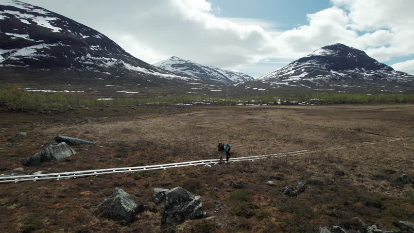 Young Couple Hiking on the Kungsleden in the Abisko National Park, Drone Shot of Hikers in a Serene Mountain Swedish Landscape, Drone Flying Sideways