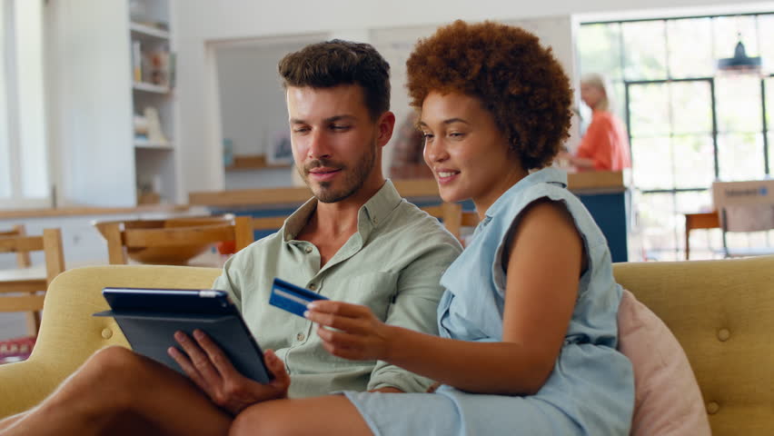 Couple at home with credit card and digital tablet making major purchase or booking dream holiday - shot in slow motion