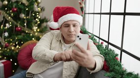Young hispanic man having video call celebrating christmas at home