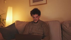Young man sitting in the living room on the sofa with laptop