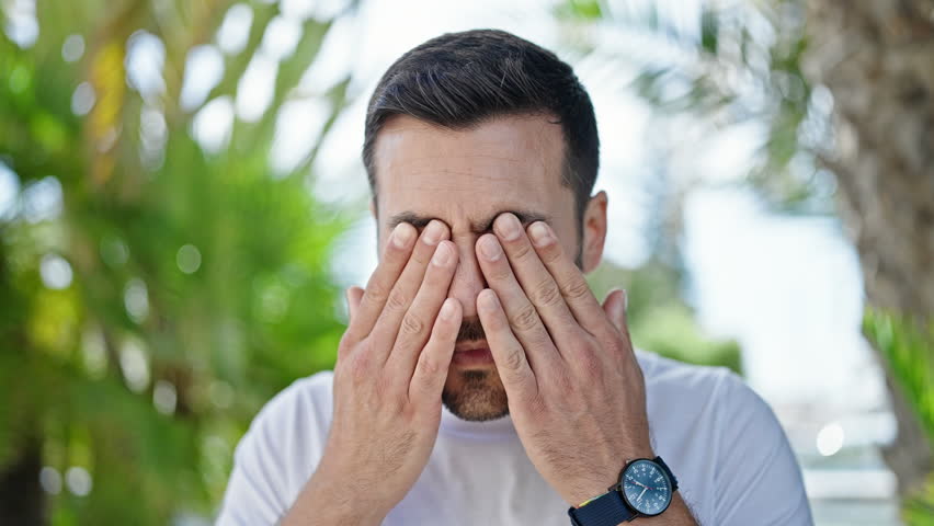 Young hispanic man standing with serious expression rubbing eyes at park Royalty-Free Stock Footage #1104448503