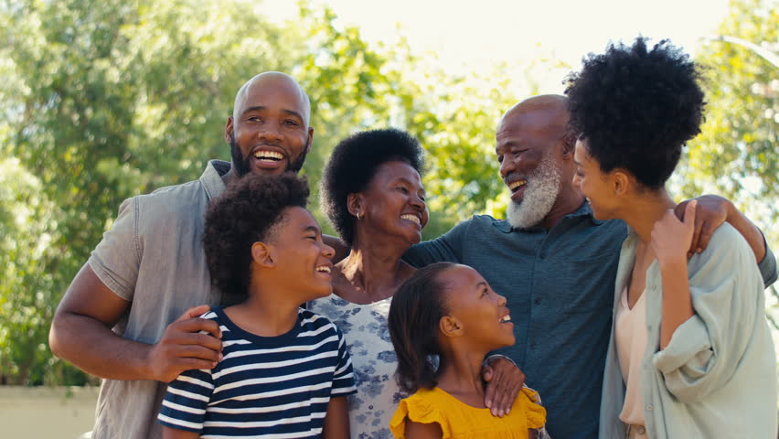 Portrait of loving multi-generation family standing outside in garden, park or countryside looking at camera- shot in slow motion