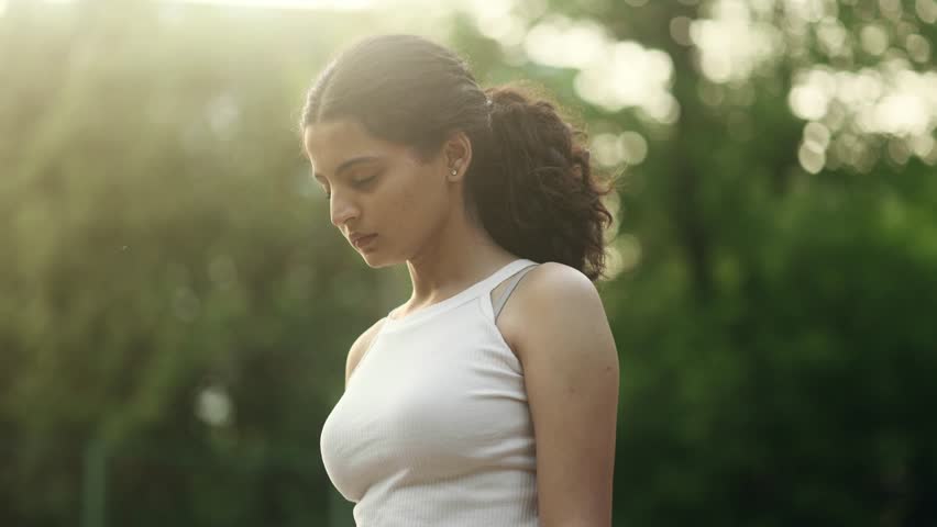 Pretty young indian woman looking ahead and exhaling fresh air taking deep breath and reducing stress at park Confident female do workout cardio for strong body outdoors Royalty-Free Stock Footage #1104450665