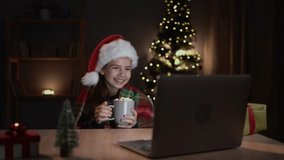 Happy child looking at laptop computer screen, eating marshmallow, seeing wonderful Christmas gifts or watching online Xmas film on cinema website