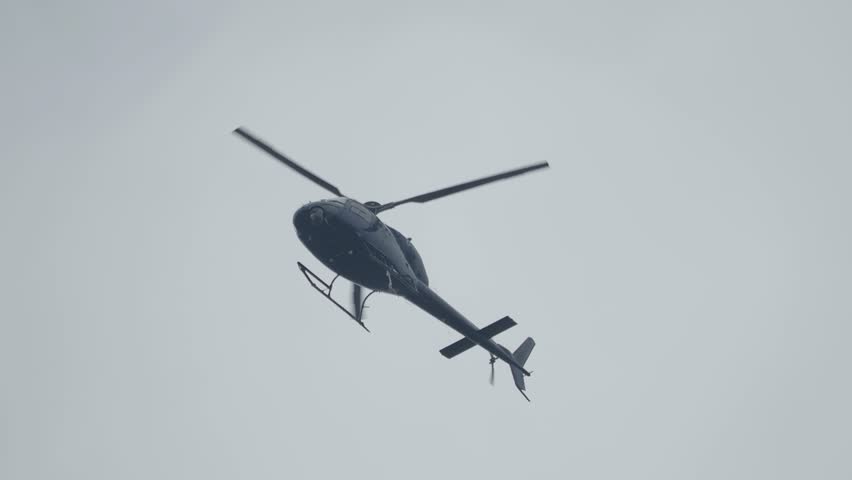 Helicopter flying in the sky low angle shot footage. Helicopter in flight. Capable of moving vertically and horizontally, the direction of motion being controlled by the pitch of the rotor blades. Royalty-Free Stock Footage #1104456265