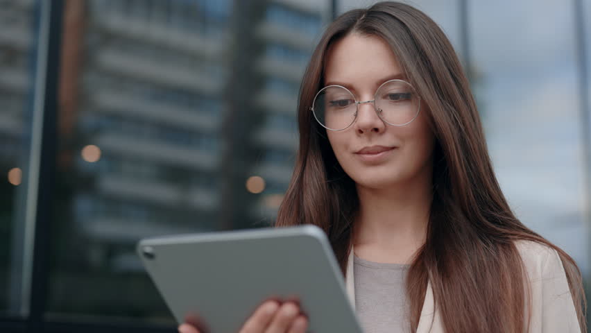 Young Attractive Woman Looking at Tablet Screen Outdoors. Elegant Businesswoman Chatting Online with Digital Device Outside. Portrait of Business Lady Using Tablet Computer Near Office Building | Shutterstock HD Video #1104458731
