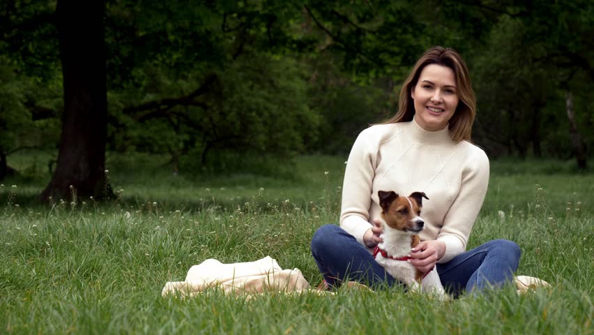 Young Jack Russell Terrier female  owner sits with his dog on the grass in the park, Wroclaw, Poland