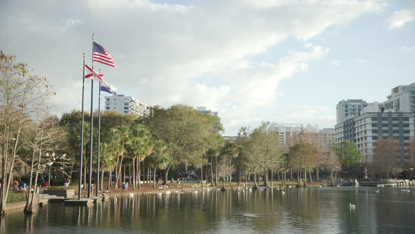 An American Flag and a Florida State flag on the edge of a lake in a park in downtown Orlando Florida.