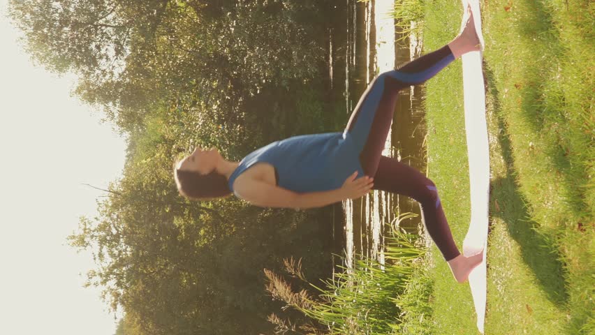 Mujer joven hacer yoga, meditación al aire libre cerca del lago