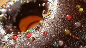 In a macro video, indulge in the sight of beautiful brown donuts, perfectly glazed, each sprinkle shining like stardust, a tantalizing treat for the senses. Snack and dessert concept. 4K HDR
