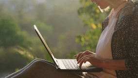 Caucasian woman typing on a keyboard and then closing laptop, while sitting on the roof outdoor in the early morning time. Female writer finished her work at sunrise. - Powered by Shutterstock - Get 15% off with code: PIKWIZARD15
