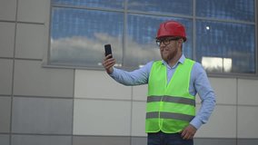 a man in a reflective vest at a construction site. a man conducts a video broadcast on a smartphone. real time video. High quality Full HD video recording