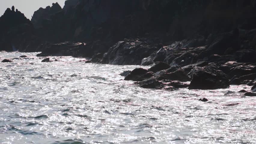Slow motion shot of sea waves striking the rocks at the shore of Kakolem Beach in Goa, India. Sea waves at the beach. Natural background. Sea waves striking on the rocks at the beach and breaking off.