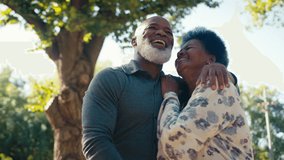 Loving senior couple outdoors in garden hugging and smiling at camera - shot in slow motion - Powered by Shutterstock - Get 15% off with code: PIKWIZARD15