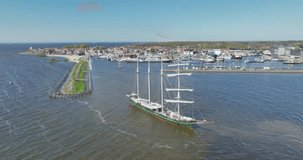 Watch in awe as a majestic sail ship gracefully docks at Urk, captured in stunning aerial drone footage from above.