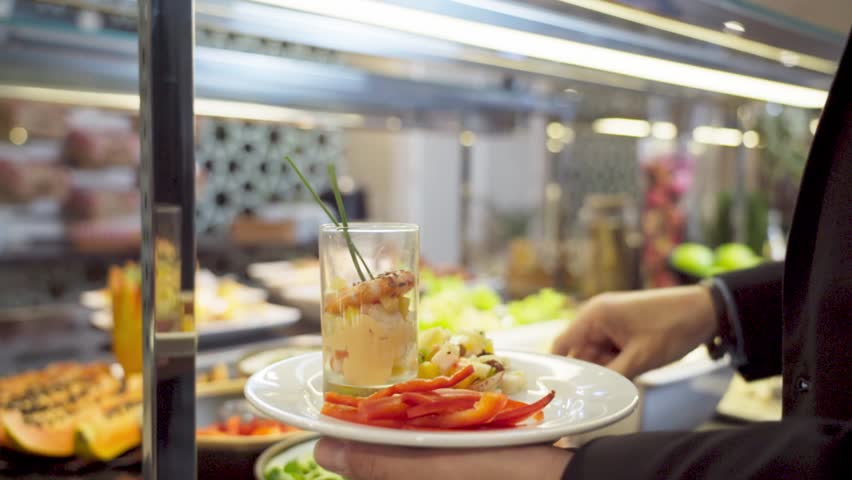 A man picks up a plate of food from a buffet in a luxury restaurant with meaty colorful fruits and vegetables. Slow motion. | Shutterstock HD Video #1104480117