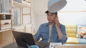 Video of a overworked chinese man working in remote doing simultaneous tasks in a home office