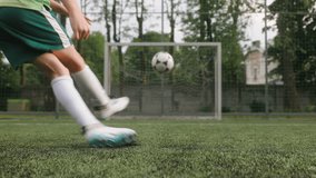 The boy dressed in football uniform is practicing on a mini football stadium. A close-up shot of the foot striking kicking the ball, resulting in a scored goal. - Powered by Shutterstock - Get 15% off with code: PIKWIZARD15