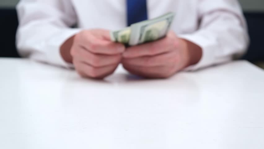 businessman in a blur counts the cash hundred-dollar bills of the USA at the table, gives them away. focus on money. close-up. the concept of venality, bribery, corruption. the hand that gives money. Royalty-Free Stock Footage #1104492313