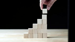 businessman stacks wooden blocks by hand to resemble a stairway, symbolizing business development and growth. Conceptualization of Business development, Financial Planning, Investment, and Strategy - Powered by Shutterstock - Get 15% off with code: PIKWIZARD15