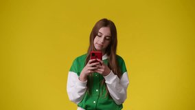 4k video of one girl using her phone over yellow background.