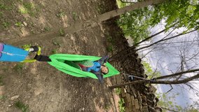 Young woman relaxes in the hammock in the garden. Vertical video