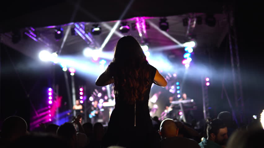 Girl at a concert seating on shoulders raising her hands Royalty-Free Stock Footage #1104502245