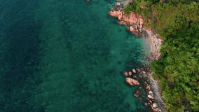 Cinematic video flying over wild beach with rocky shore and sandy coves in tropics. Flight over shore of tropical island with clear water. Top view of shore of tropical island for relaxation