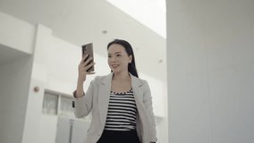asian senior businesswoman using smartphone she walking and video call commuting at office building