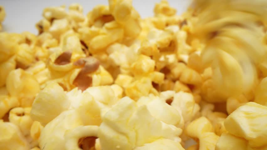 In a macro video captured with a probe lens, the scattered popcorn on the floor comes to life. showcasing its unique shape, texture, and golden hues. Crumbs and remnants create an intricate mosaic. 4K