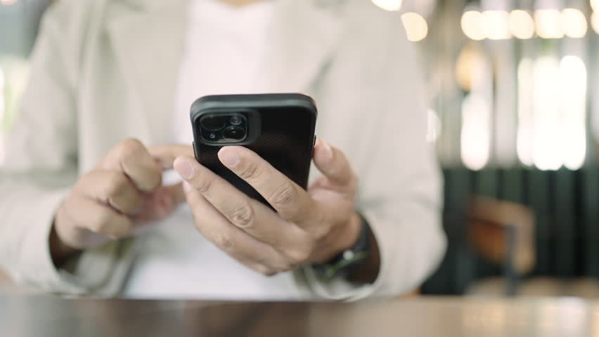 Close up the hand using smartphone touching display and scrolling working new job on internet at coffeeshop | Shutterstock HD Video #1104505681