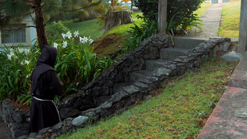 Franciscan friar catholic, christian religious monk meditating and praying walking on the path on a path contemplating nature in the forest at dawn climbing stone stairs up the slope of the forest