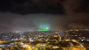 Drone hyperlapse of the fog moving around the green mountain at night in Abha city, Saudi Arabia