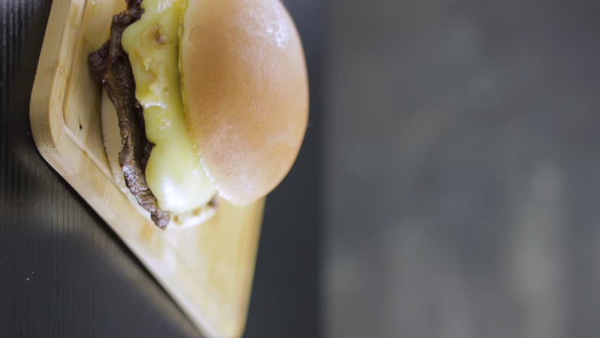 Barros Luco sandwich: beef with melted cheese. Hand placing Chilean Fiestas Patrias paper cup, on black table and vertical wooden board with copy space concept of typical Chilean food