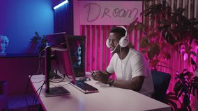Victorious Black Male Gamer: Headset-wearing Gamer Expresses Thrill and Excitement after Winning Battle in Online Cyber Tournament, Captured in Joyful Portrait at Night
