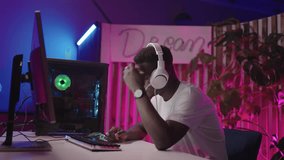 Medium Portrait of Unhappy African American Gamer Reacting Emotionally to Loss in Computer Game: Professional Cyber Athlete Playing Online Video Games and Streaming his Gameplay - Powered by Shutterstock - Get 15% off with code: PIKWIZARD15