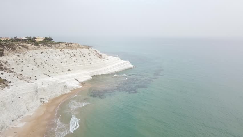 Scala dei Turchi in Sicily, white rocks overhanging the crystalline blue sea. Cloudy day. Overview from the drone, underwater reefs. | Shutterstock HD Video #1104515607