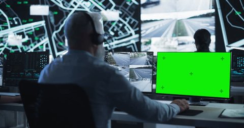 Technical Support Manager Using Headphones and a Computer with Green Screen Mock Up Display. Specialist in a Dark High-Tech Monitoring Room, Concentrated on a Call and Computer Work Adlı Stok Video