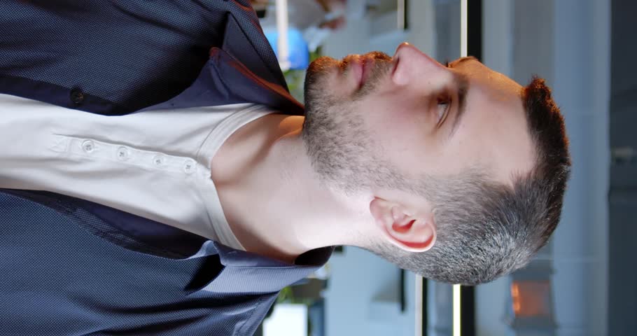 Vertical shoot. Portrait of mature man. Man with brown eyes turnes head and posing for camera. Man with beard on unfocused background. Attractive guy dressed up in business clothes.
