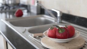Focus on vegetables in a plate, in the background is the hand of a man washing red bell peppers with water in the kitchen. - Powered by Shutterstock - Get 15% off with code: PIKWIZARD15