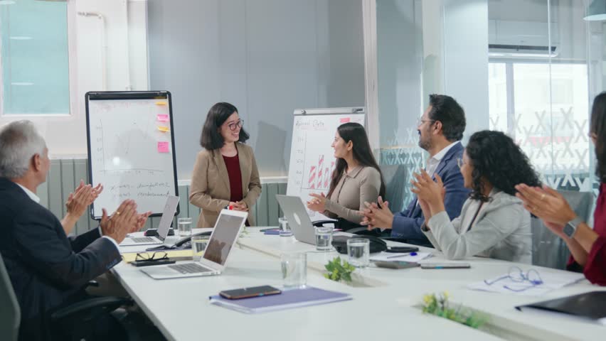 A young modern corporate Asian girl or female executive giving a presentation is appreciated or applauded by a diverse team of colleagues in a conference room meeting in a start-up office or business - Powered by Shutterstock - Get 15% off with code: PIKWIZARD15