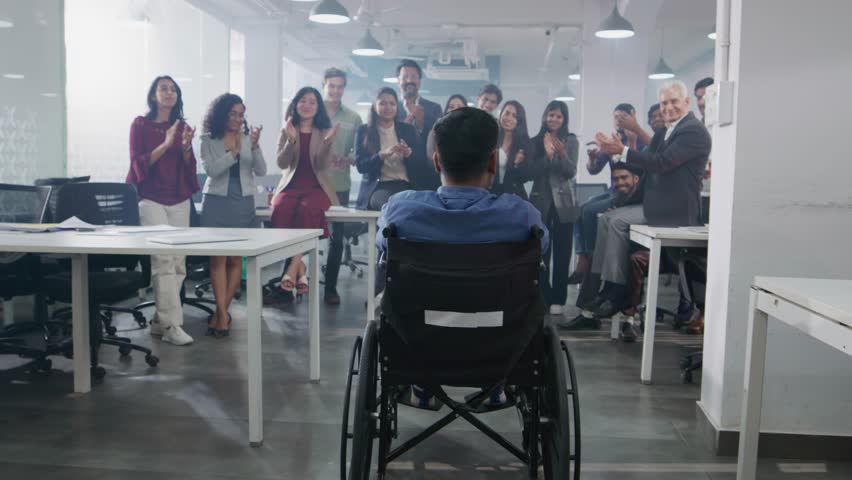 A group of happy smiling Indian Asian team members or office employees celebrating the success of a disabled or handicapped male or man by clapping or cheering in a modern corporate start up workspace Royalty-Free Stock Footage #1104522955