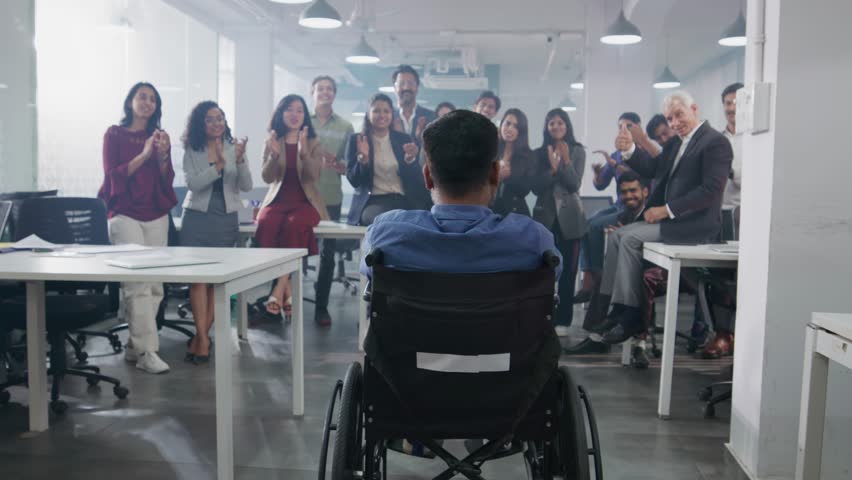 A group of happy Indian Asian team members or office employees celebrating the success of a disabled or handicapped male or man by clapping or cheering in a modern corporate start up workspace  | Shutterstock HD Video #1104522955