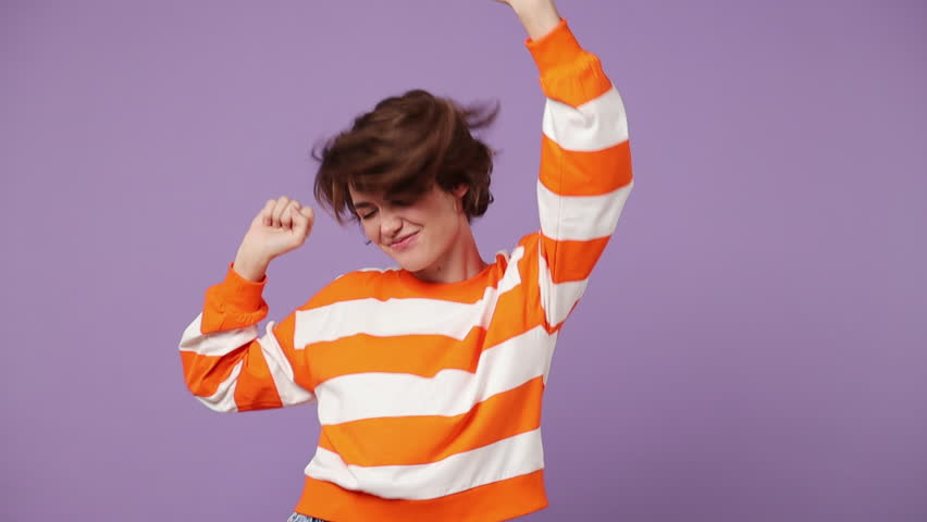 Fancy vivid happy bright young woman wear casual clothes dance waving rising have fun enjoy relax celebrate play fluttering hair isolated on plain pastel purple background. People lifestyle concept