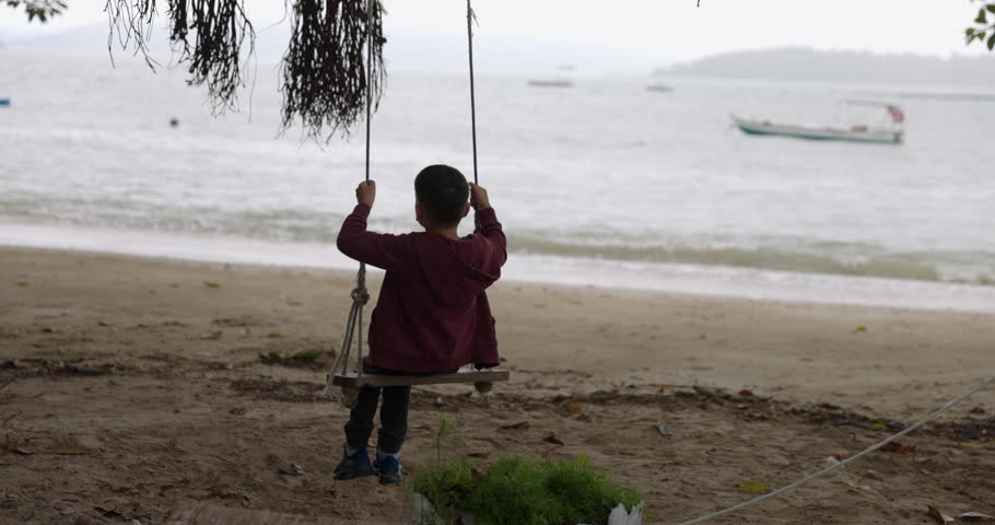 Boy on rope swing overlooking ocean on tropical beach - carefree | Shutterstock HD Video #1104527237