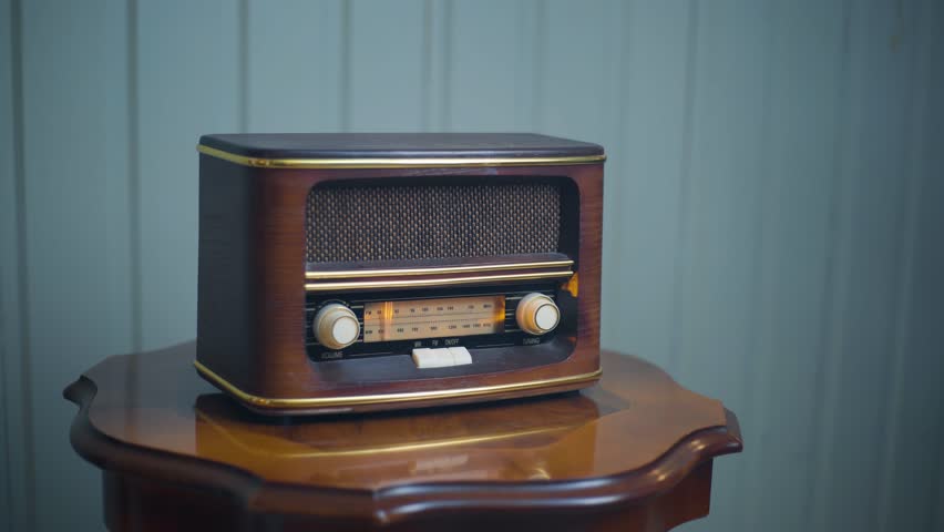 An old vintage radio put on the small wooden table against the blurry wall