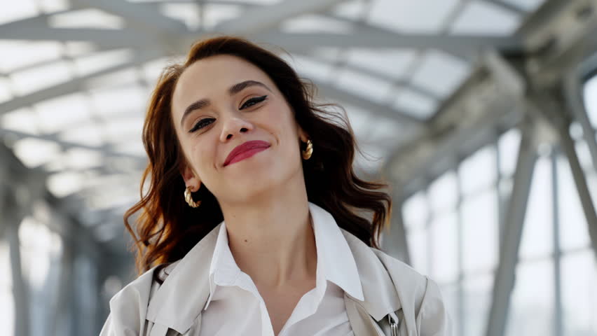 Happy girl with a big smile walking along a pedestrian crossing. A business lady smiles at the camera.