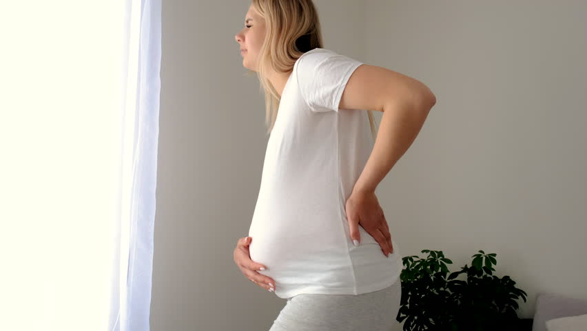 Pregnant woman hurts her back. Selective focus.